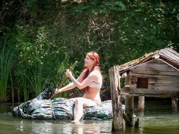 Frau paddelt auf improvisiertem Floß in einem Gewässer