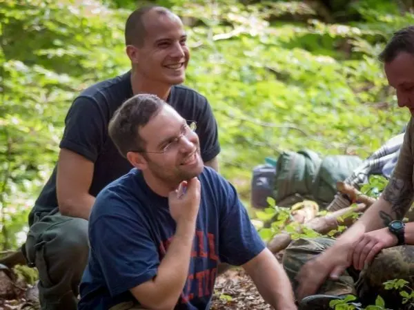 Grüne Waldlandschaft mit mehreren Personen, die entspannt auf dem Boden sitzen