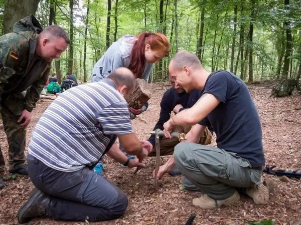 Gruppe arbeitet gemeinsam an einem Holzstück im Wald