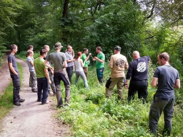 Gruppe diskutiert im Wald über Überlebenstechniken und Naturkenntnisse