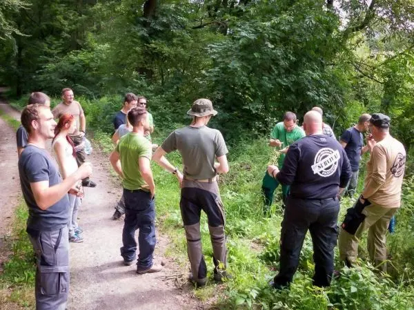 Gruppe diskutiert Techniken im Wald, einige halten Ausrüstung in den Händen