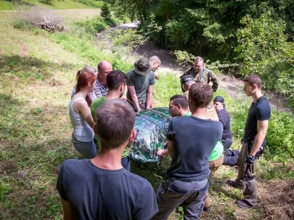 Gruppe hebt eine improvisierte Trage mit einer Decke in der Natur an