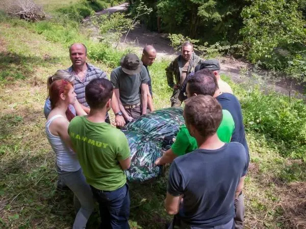 Gruppe hebt eine Tarp-Notunterkunft gemeinsam an einem Waldrand