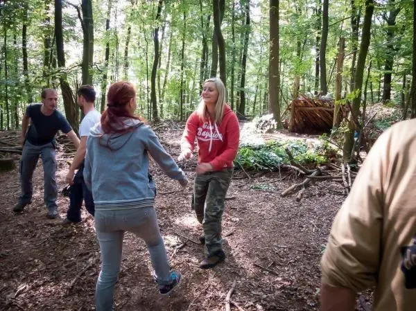 Gruppe von Personen steht im Wald und interagiert miteinander beim Überlebenstraining