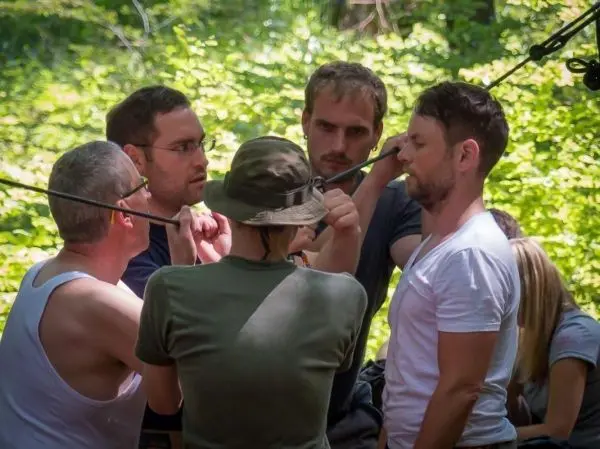 Gruppierung arbeitet gemeinsam an einer selbstgebauten Seilquerung im Wald