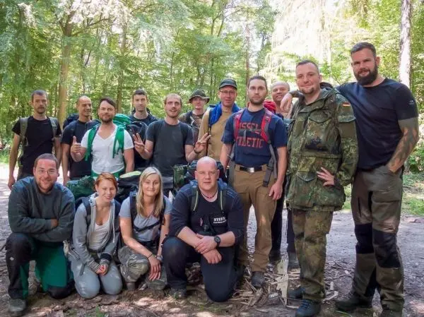 Gruppierung von Personen mit Rucksäcken im Wald, einige posieren für das Foto