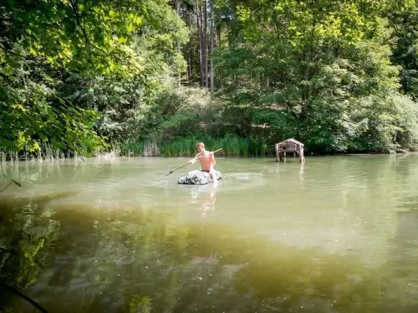 Junge paddelt auf einem großen Stein in einem stillen Gewässer