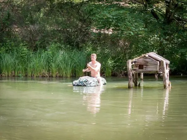 Junge paddelt auf improvisiertem Floß in einem Gewässer