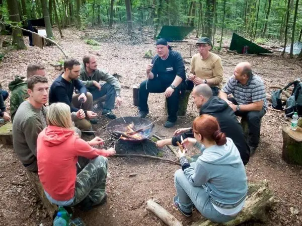 Lagerfeuer brennt in der Mitte einer Gruppe, die auf Baumstämmen sitzt