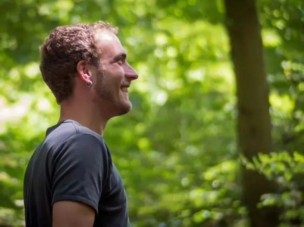 Lichtdurchfluteter Wald mit einer Person, die lächelt und nach oben schaut