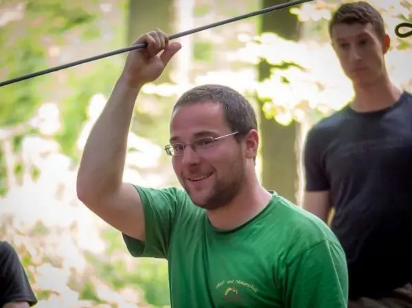 Mann hält einen Stock über Kopf, im Hintergrund eine weitere Person