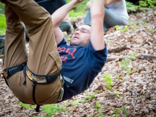 Mann in Kletterausrüstung überquert eine selbstgebaute Seilbrücke