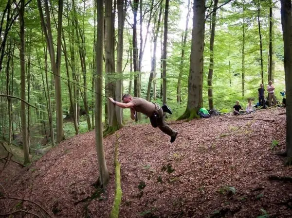 Mann überquert mit Seil eine Steilwand im Wald