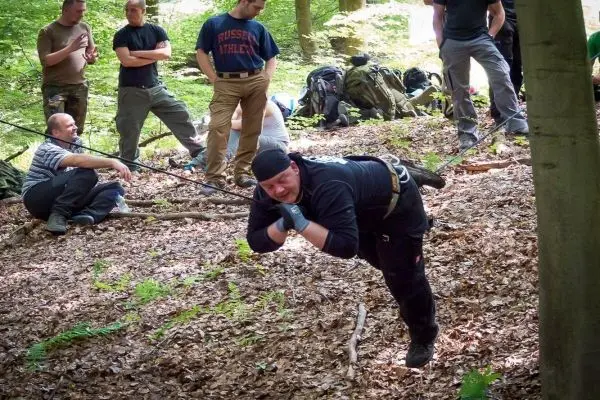 Mann überquert selbstgebaute Seilbrücke zwischen Bäumen im Wald