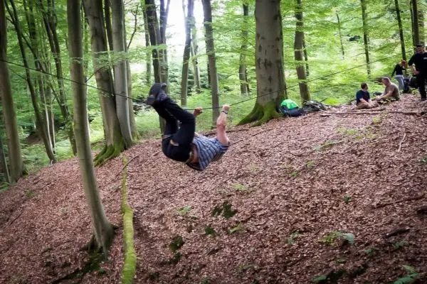 Mann überquert selbstgebaute Seilbrücke zwischen Bäumen im Wald