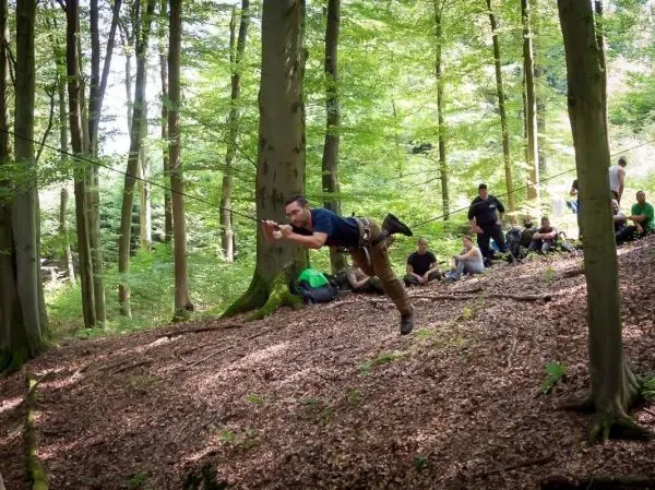 Mann überquert selbstgebaute Seilbrücke zwischen Bäumen im Wald