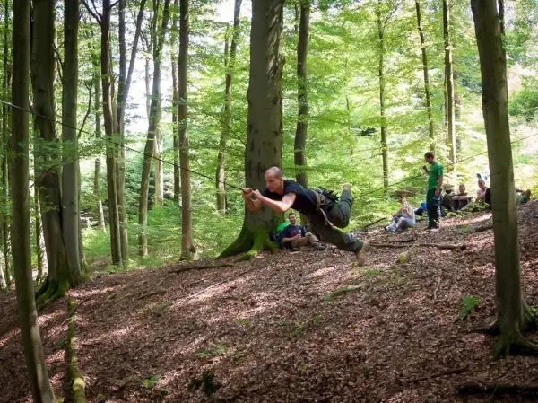 Mann überquert selbstgebaute Seilbrücke zwischen Bäumen im Wald