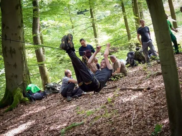 Mann überquert selbstgebaute Seilbrücke zwischen Bäumen im Wald