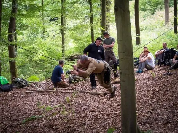 Mann überquert selbstgebaute Seilbrücke zwischen Bäumen im Wald