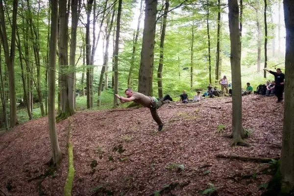 Mann überquert selbstgebaute Seilbrücke zwischen Bäumen im Wald