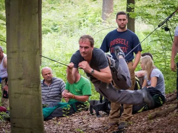 Mann überquert selbstgebaute Seilbrücke zwischen zwei Bäumen