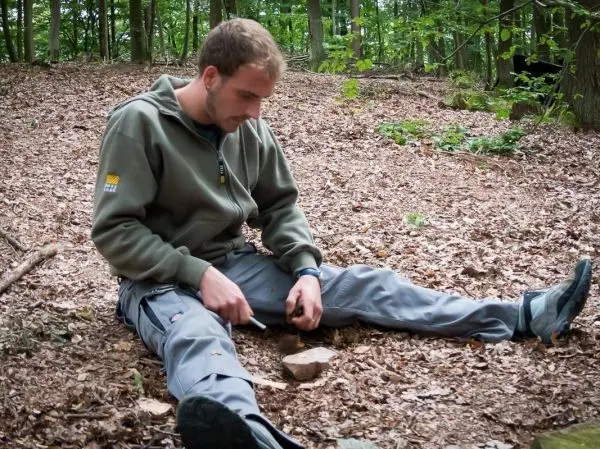 Messer bearbeitet Stein auf dem Waldboden zwischen Laub