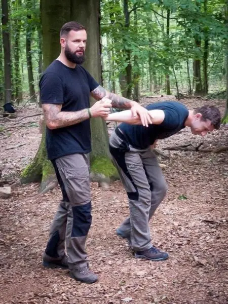 Person demonstriert eine Technik an anderer Person im Wald
