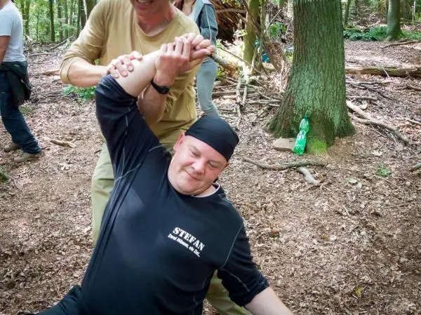 Person hilft anderer Person beim Üben einer Technik im Wald