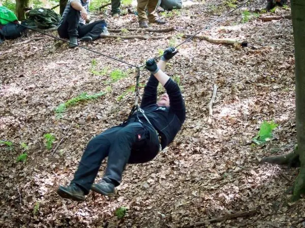 Person nutzt selbstgebaute Seilquerung, um einen Hang zu überwinden