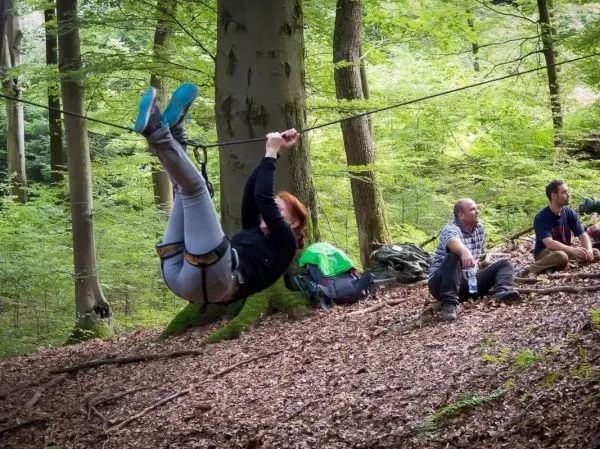 Person nutzt selbstgebaute Seilquerung zwischen Bäumen im Wald