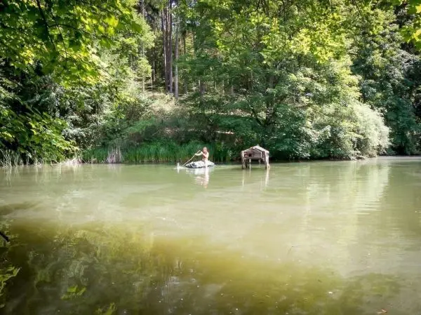 Person paddelt auf einem kleinen Boot in einem ruhigen Gewässer