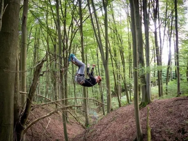Person schwingt an einer selbstgebauten Seilbrücke im Wald
