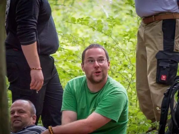 Person sitzt im gruenen und schaut ueberrascht zu anderen personen