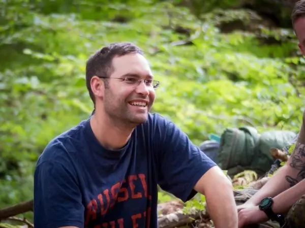 Person sitzt laechelnd im gruenen