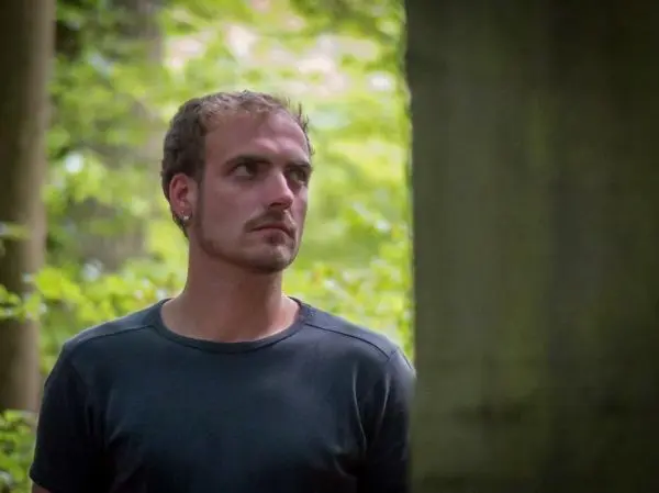 Person steht im wald und schaut nachdenklich zur seite