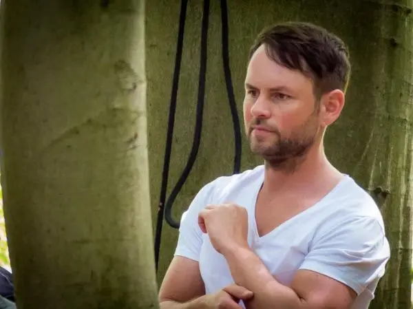 Person steht neben einem Baum und betrachtet die Umgebung