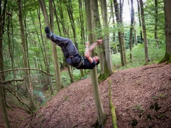 Seilquerung zwischen Bäumen mit gesichertem Klettergurt und Seil