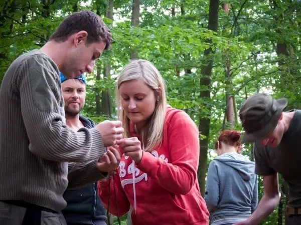 Zwei Personen binden gemeinsam eine Schnur im Wald