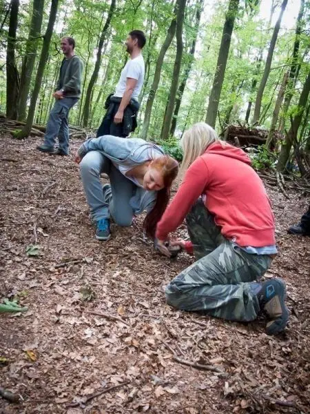 Zwei Personen knien im Wald und bearbeiten den Boden
