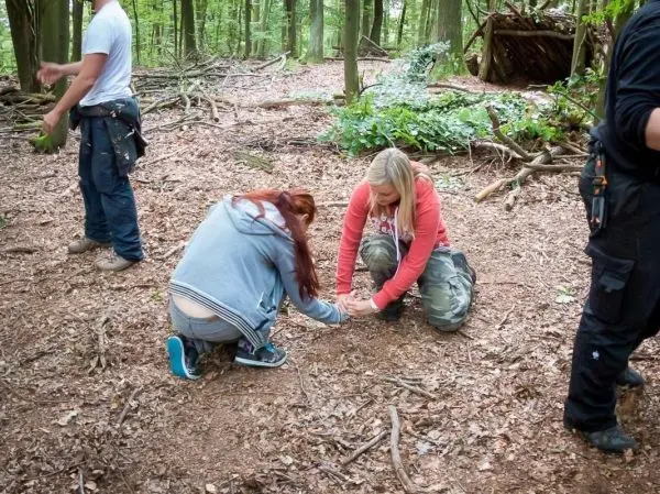Zwei Personen knien im Wald und bereiten Zunder vor