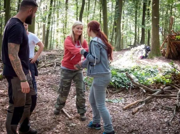 Zwei Personen schütteln sich die Hände im Wald, während zwei weitere zuschauen