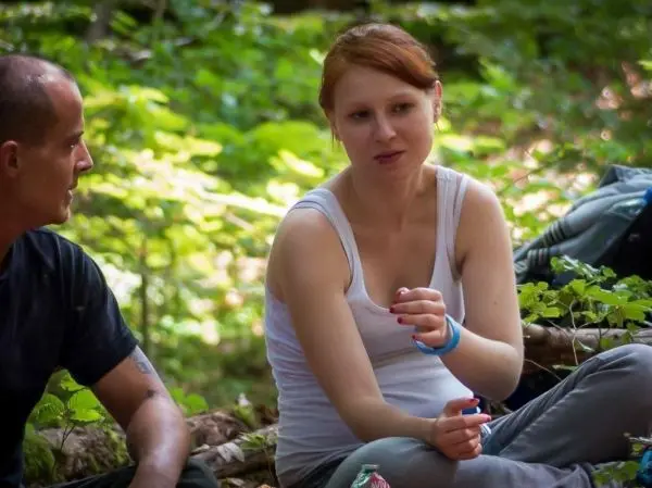 Zwei Personen sitzen im Wald auf dem Boden und unterhalten sich