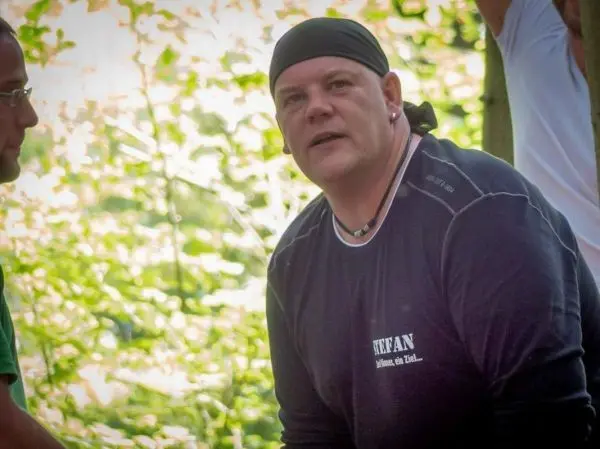 Zwei Personen stehen im Wald, eine Person schaut aufmerksam