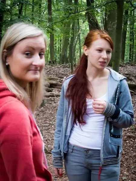 Zwei Personen stehen im Wald und unterhalten sich