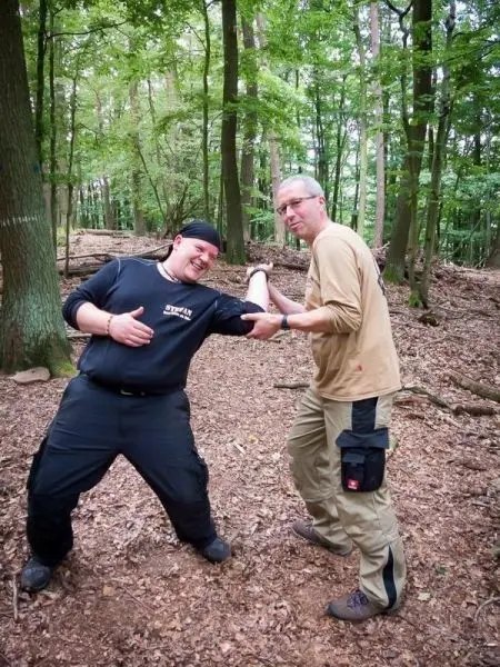 Zwei Personen stehen in einem Wald und zeigen eine Interaktion