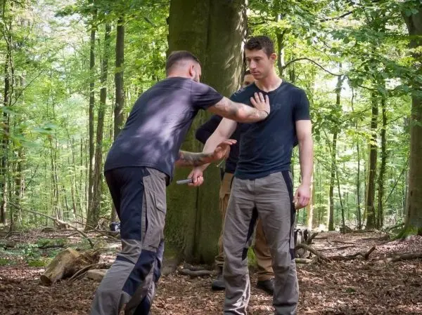 Zwei Personen üben eine Selbstverteidigungstechnik im Wald