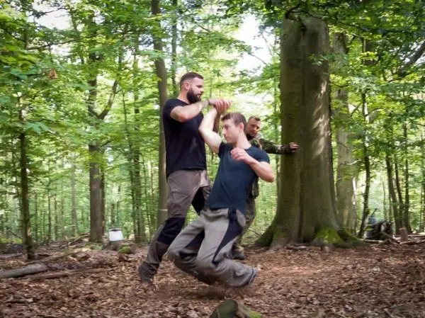 Zwei Personen üben eine Selbstverteidigungstechnik im Wald