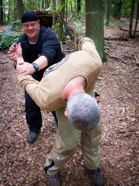 Zwei Personen üben eine Selbstverteidigungstechnik im Wald