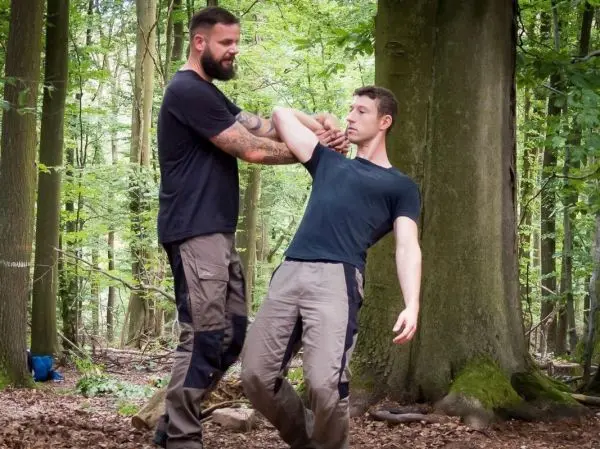 Zwei Personen üben eine Selbstverteidigungstechnik im Wald