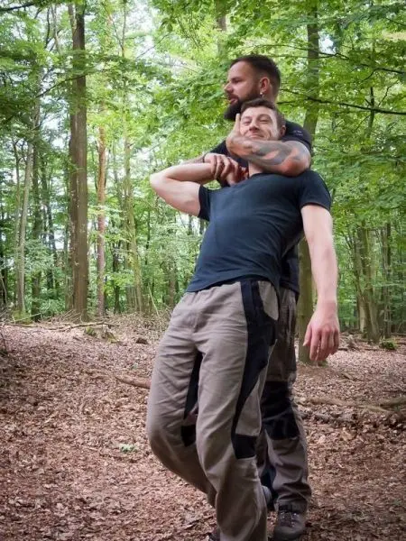 Zwei Personen üben eine Selbstverteidigungstechnik im Wald aus